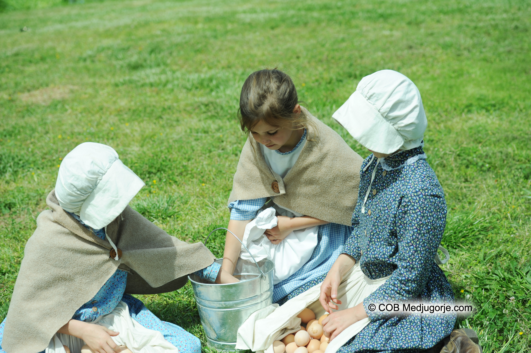 Faith, Victoia, and Angela pick up eggs in their 'old-fashioned' outfits
